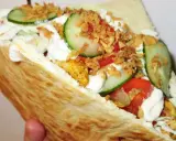 Pyszna bułka kebab z kurczakiem, warzywami i chrupiącą cebulką.