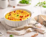 Pyszny omlet z airfryer, z kawałkami kiełbasy i papryki, udekorowany natką pietruszki, gotowy do podania.