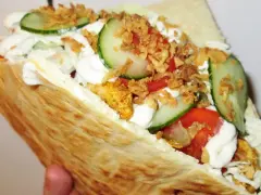 Pyszna bułka kebab z kurczakiem, warzywami i chrupiącą cebulką.