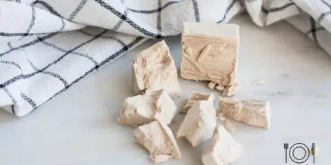 Świeże drożdże pokruszone na blacie. Idealne do ciasta drożdżowego, które pieczemy w odpowiedniej temperaturze.