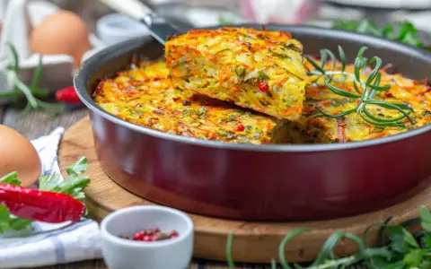 Pyszna, kolorowa zapiekanka warzywna z ziołami – idealna zdrowa kolacja. Widać jajka, papryczkę chili i rozmaryn.