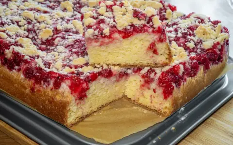 Puszyste ciasto drożdżowe z suchych drożdży z malinami i kruszonką, pokrojone na kawałki.