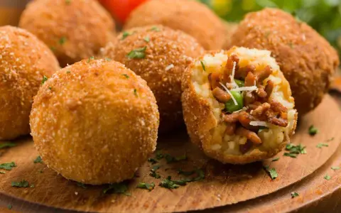Chrupiące arancini, pyszne włoskie dania z ryżu, mięsa i groszku, posypane parmezanem.