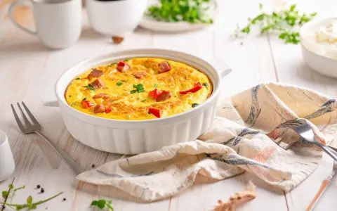 Pyszny omlet z airfryer, z kawałkami kiełbasy i papryki, udekorowany natką pietruszki, gotowy do podania.