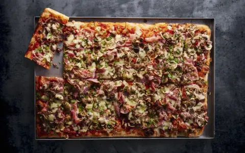 Domowa pizza na blachę z szynką, pieczarkami i oliwkami. Idealna na rodzinne spotkanie, łatwy przepis.