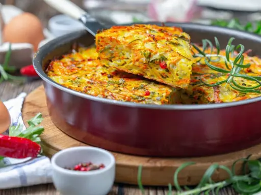 Pyszna, kolorowa zapiekanka warzywna z ziołami – idealna zdrowa kolacja. Widać jajka, papryczkę chili i rozmaryn.