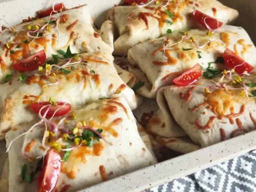 Tortilla z mięsem mielonym i serem, zapieczona z pomidorkami i kiełkami. Pyszne danie gotowe do podania.