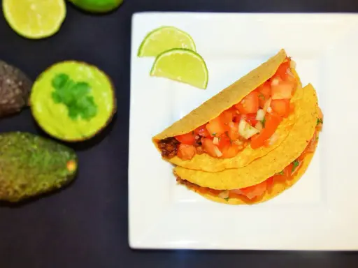 Pyszne meksykańskie tacos przepis na talerzu, z awokado i limonką w tle. Idealne na szybki obiad!