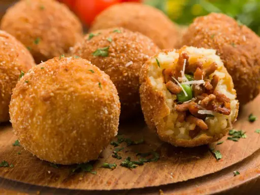Chrupiące arancini, pyszne włoskie dania z ryżu, mięsa i groszku, posypane parmezanem.
