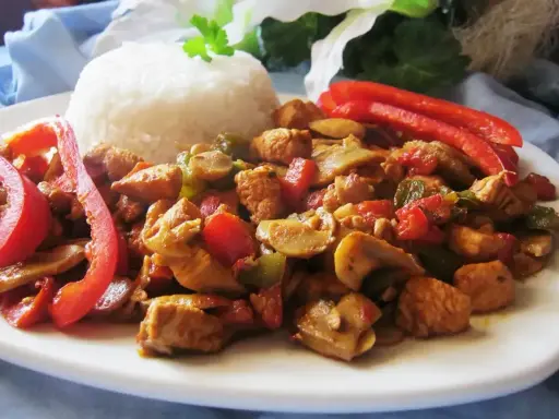 Pyszny kurczak po chińsku w sosie sojowym z ryżem, papryką i pieczarkami.