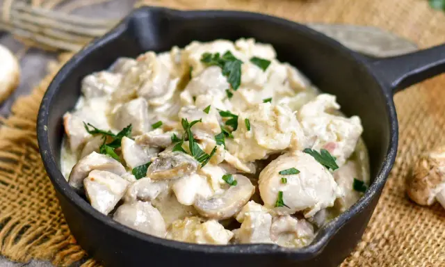 Pyszny kurczak w sosie pieczarkowym, jak u Ani, w czarnej patelni, ozdobiony natką pietruszki.